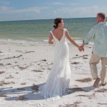 A bride and groom walking on the beach