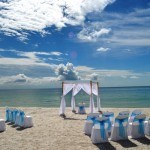 A beach with chairs and tables set up for an outdoor wedding.
