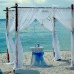 A wedding set up on the beach with a table and chairs.