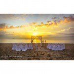 A sunset on the beach with chairs and an arch