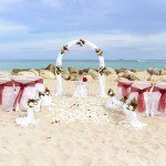 A beach wedding with red and white flowers