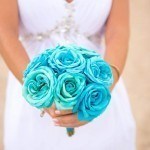 A bride holding her bouquet of blue roses.