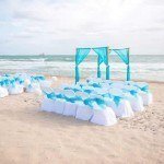 A beach wedding with white and blue chairs