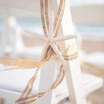 A white chair with a starfish and ribbon tied around it.