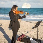 A violinist playing at a beach wedding