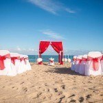 A beach wedding with red and white decor