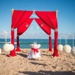 A red and white wedding set up on the beach