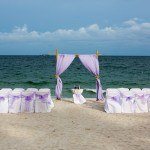 A wedding set up on the beach with purple and white decor.