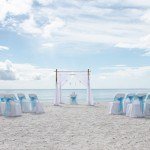 A beach wedding with blue and white chairs