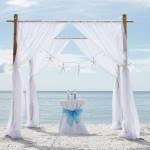 A wedding arch on the beach with blue decorations.
