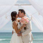 A newly married couple kissing under an awning.
