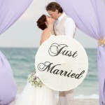 A bride and groom kissing under an umbrella.