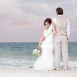 A bride and groom standing on the beach