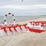 A beach wedding with red and white decorations