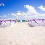 A beach wedding with purple and white decor.