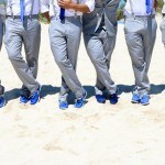 A group of men in grey pants and blue shoes.