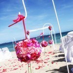 A beach with pink flowers and white chairs