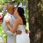 A man and woman kissing in front of a tree.