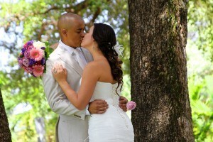 A man and woman kissing in front of a tree.