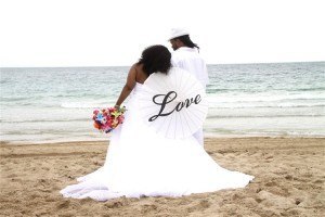 A couple is sitting on the beach with their wedding dress.