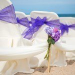 A purple bouquet sitting on top of white chairs.