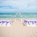 A beach with two chairs and an arch in the sand.
