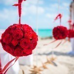 A red rose ball on the beach for a wedding.
