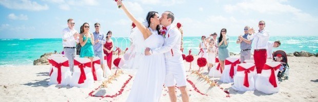 A couple kissing on the beach while others watch.