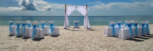 A wedding set up on the beach with white curtains.