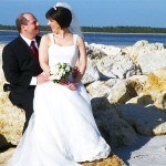 A bride and groom sitting on beach rocks