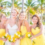 A group of women in yellow dresses holding flowers.