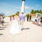 A couple walking on the beach with their wedding guests.
