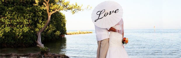 A bride and groom holding an umbrella with the word Love