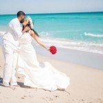 A bride and groom kissing on the beach