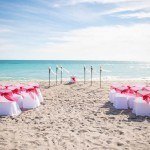 A beach with chairs and tables set up for an event.