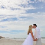 A bride and groom kissing on the beach