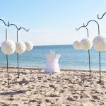 A beach wedding with white flowers and a blue sky
