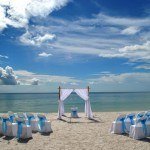 A beach with chairs and an arch for a wedding.