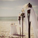 A beach wedding with white flowers and umbrellas