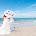A newly married couple on the beach under an umbrella
