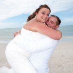 A man and woman hugging on the beach.