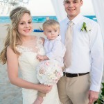 A bride and groom with their son on the beach.