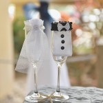 Two wine glasses with a wedding dress and tuxedo on them.