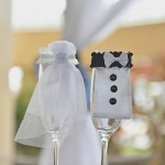 A couple of wine glasses with wedding attire on them.