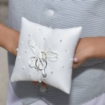 A person holding a ring pillow with two rings on it.